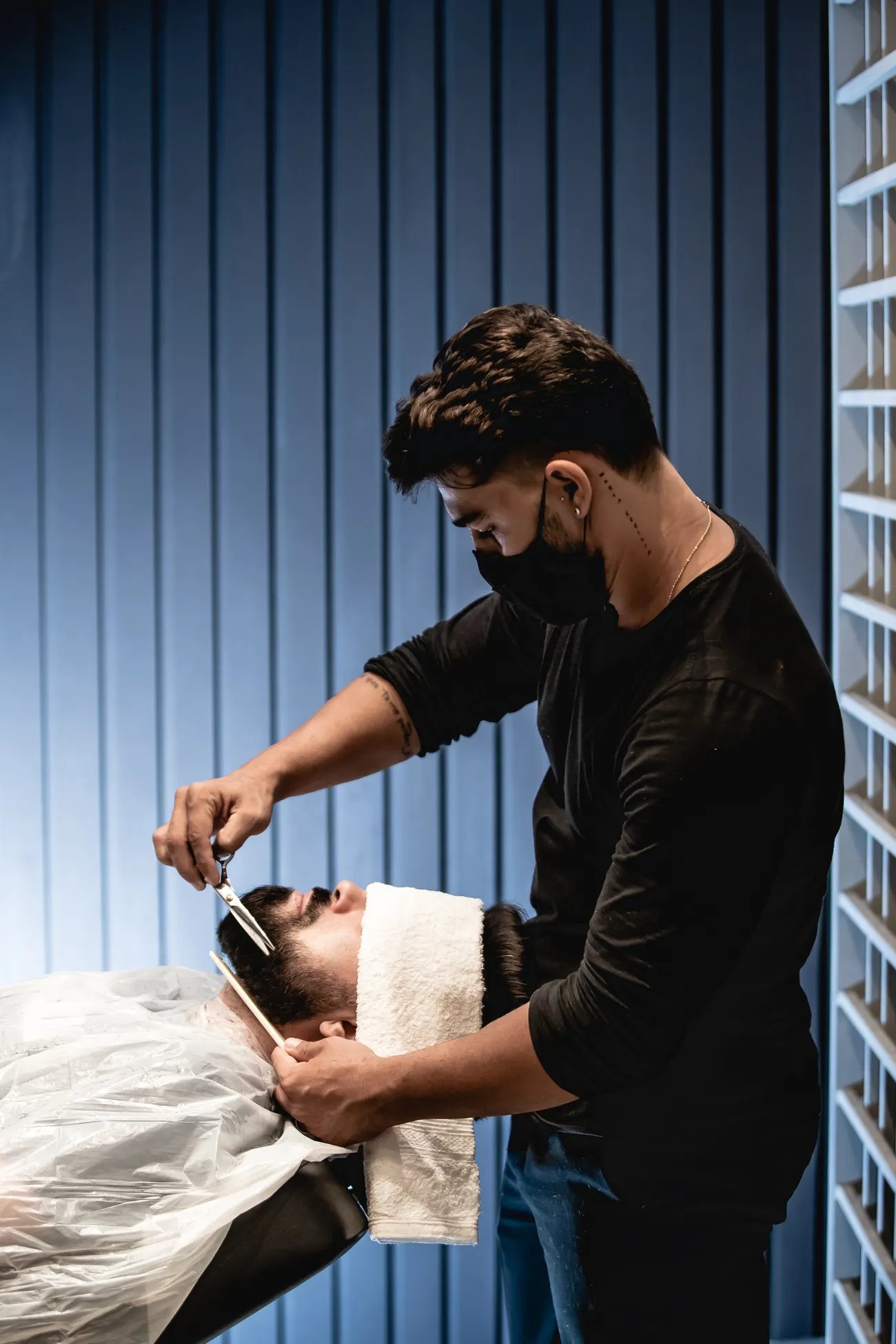 Barbeiro aparando a barba de um cliente